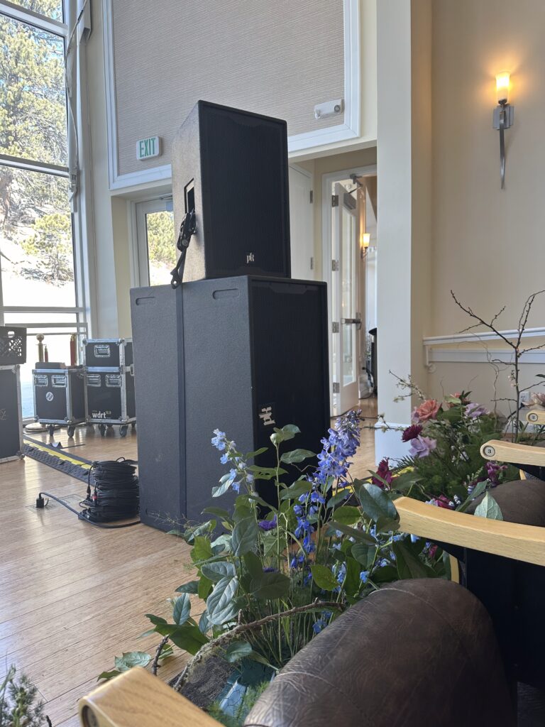 Wedding production setup with PK Sound speakers and floral arrangements at a Colorado venue